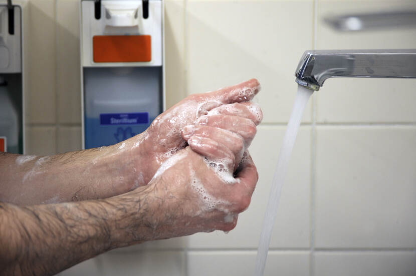 Man wast handen onder kraan