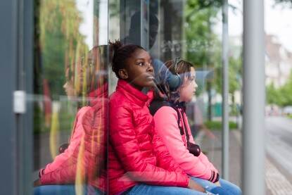 Twee meisje zitten op een bankje bij een bushalte