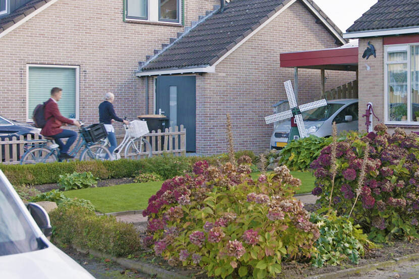 Een wijkverpleegkundige en een inspecteur komen op de fiets aan bij het huis van een cliënt